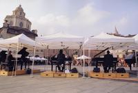 Antonio Ballista dirige "Musiche per 21 pianoforti di Daniele Lombardi" in Piazza Castello